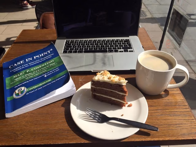 Case study notes beside a laptop and coffee
