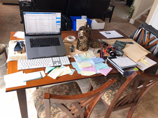 Research notes and a laptop on a busy desk